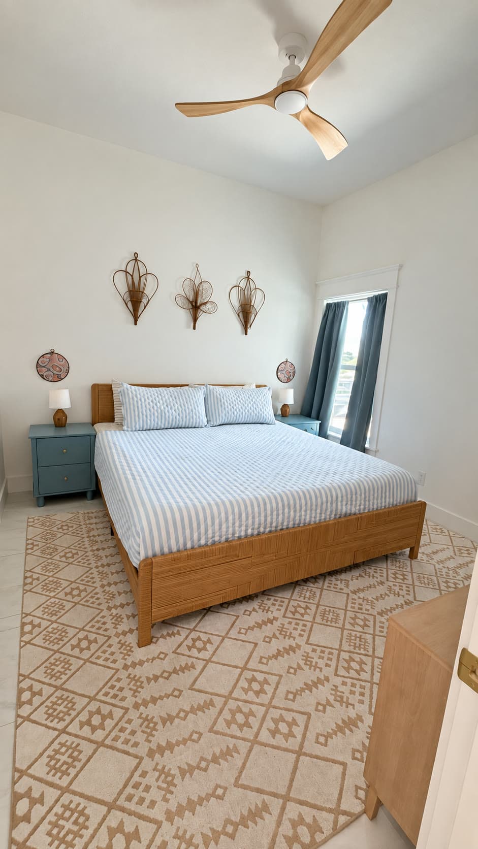 Guest bedroom after cleaning: Made bed with blue striped bedding, clear nightstands, and a clean patterned rug